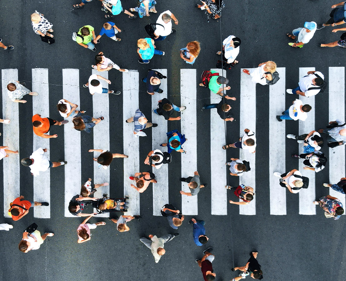 Aerial view of diverse people forming on a crossing with text overlay 'Public Policy' describing the company's focus on improving community health through collaborative efforts.
